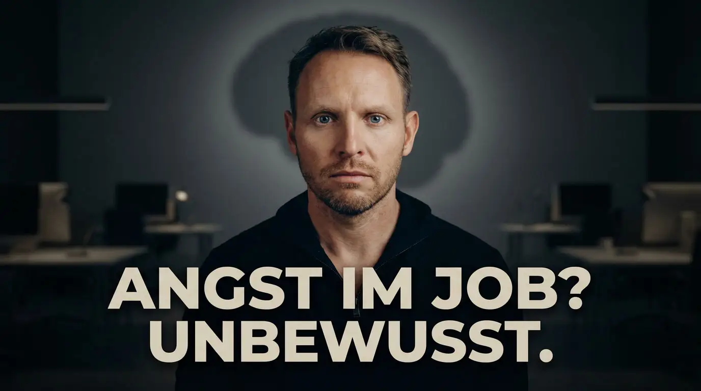 Mann steht in einem büro und schaut fokussiert zum zuschauer. davor steht "Angst im job unbewusst"